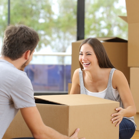 Happy couple or marriage lifting boxes moving home